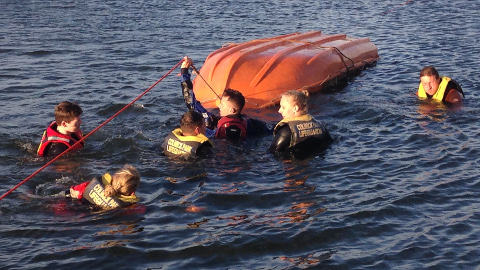Group of lifeguards performing a boat capsize training exercise